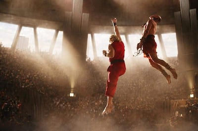 Luchadores en camiseta roja realizan acrobacias en un estadio iluminado, rodeados de una multitud emocionada.